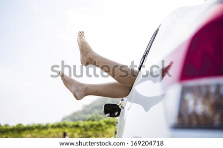 Woman legs out the windows in car above the clouds (Summer road trip car vacation concept)