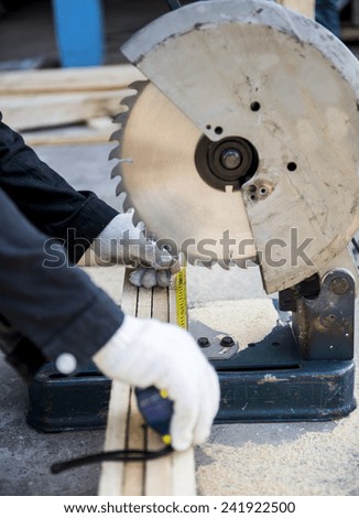 Carpenter cutting wood with electric saw