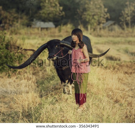 Asian woman listening radio with her buffalo, Thailand (vintage color)