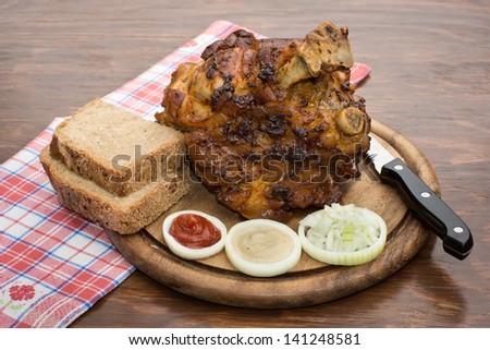 Roasted pork knee on a serving board with bread and knife