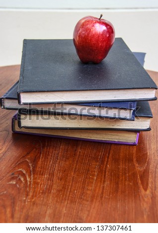 red apple and  old books  on wooden tabletop