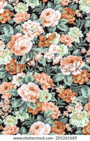 Orange vintage rose on black fabric background, Fragment of colorful retro tapestry textile pattern with floral ornament useful as background.