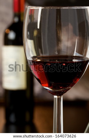Wineglass with red wine and a bottle in the background