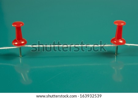 thumbtacks red and white wire on green background