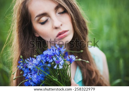 woman with eyes closed. girl in a field in the setting sun with a bouquet of cornflowers. woman with a bouquet of cornflowers
