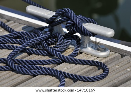 Close up of a blue rope tied up on a bitt securing boat to jetty