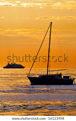 Two different kind of boats at sunset: a big yacht and a small sailboat
