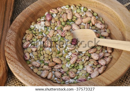 Wooden bowl within beans, lentils, chick-peas and rice and a wooden ladle