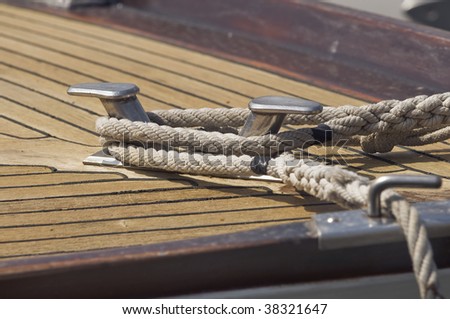 Ropes tied up on a bitt of a wooden boat
