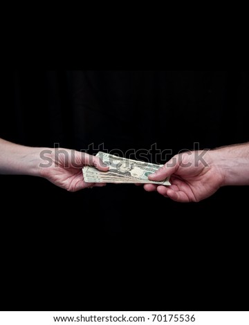 Caucasian man hands his wife one hundred dollars in U.S. currency. Twenty dollar bills. Against a black background. Hands and wrists only.