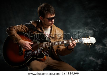 young guy playing guitar in the studio