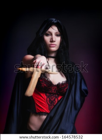 photo session in studio of the young girl in style art with an unusual makeup a girl in cloak and sword