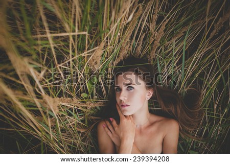 The beautiful young woman with long hair  lying down on grass.