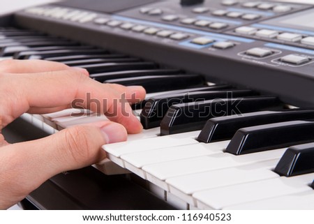 Black and white piano keys and hand fingers pressing the keys.