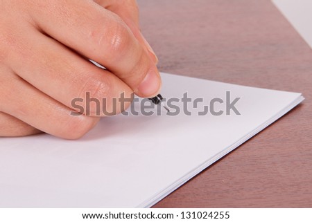 Close up, women hand writing to an empty paper with pen on wooden table.