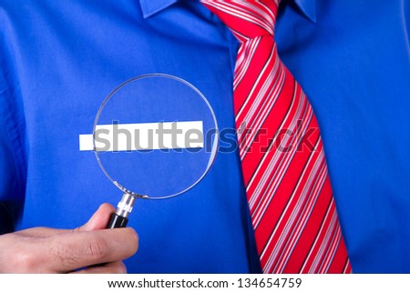 Businessman with red tie and blue shirt showing his blank label title with magnifying glass.