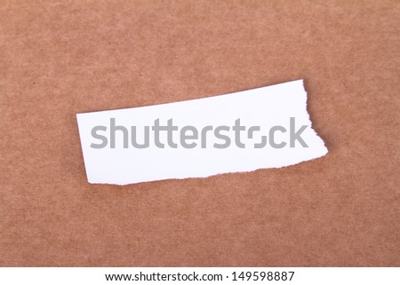 White torn piece of paper on brown background.