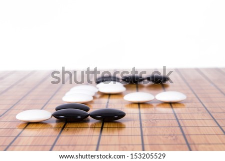 White stone standing out from black pieces on Chinese go game board, isolated on white background.