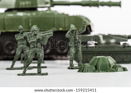 Miniature toy soldiers and tank, isolated on white background.