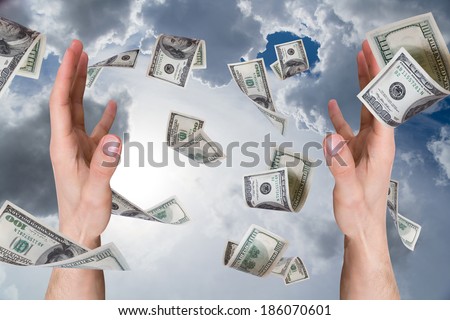 One hundred dollar money banknotes flying and falling on young male hands, cloudy background.