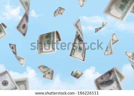 Dollar banknotes falling down with depth of field on cloudy sky background.