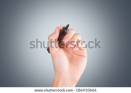 Young male hand holding pen with copy space on dark background.