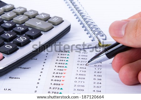 Hand holding pen and analyzing financial data for better results.