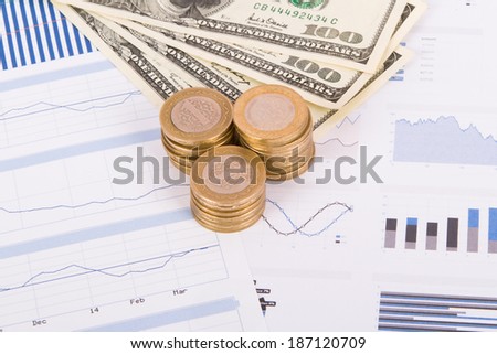 Dollar banknotes and coins on bar chart graphic results.