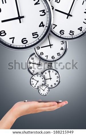 Time concept, hand holding smart phone and analog clocks around it.