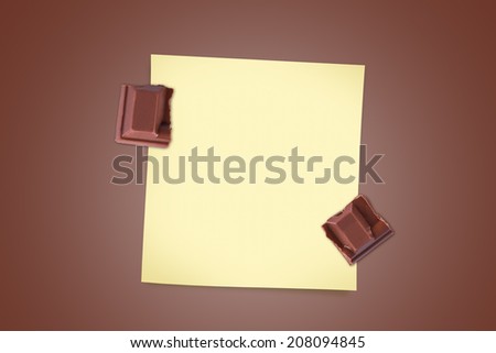 Top view of milk bar chocolate pieces with yellow sticky note paper for your message on brown background.