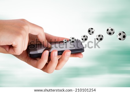 Football subject, hand holding mobile phone on blurry fast background.