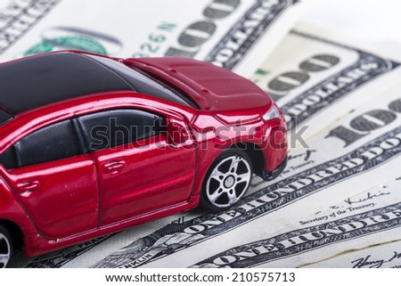 Red, small, toy car on one hundred dollar banknotes deck.