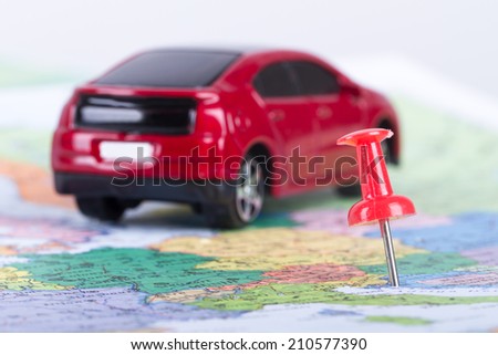 Pushpin and small, toy car on map for travel concept.