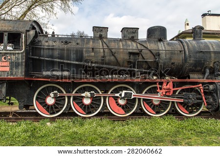 Front view of black old train wagon, in cloudy sky.