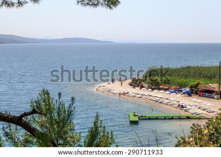 MUGLA, TURKEY - JUNE 1, 2015 : Side view of green wooden pier on beach with sunbeds and umbrellas, on sunny sky background in Gokova.