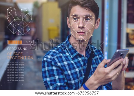 Biometric verification. Modern young man with the phone. The concept of a new technology of face recognition on polygonal grid is constructed by the points of IT security and protection