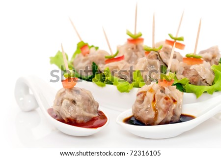 Chinese steamed dumplings (also known as Dim Sum) served with oyster sauce and spicy sauce on ceramic spoons, on white background.