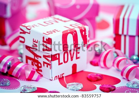 Small gift boxes with the word LOVE, ribbons, hearts and gems.