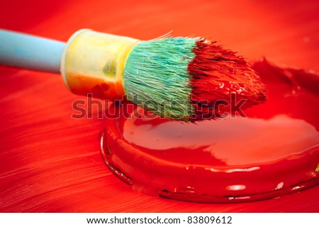 Closeup of a red paintbrush and red paint cover.