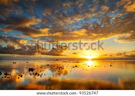 A spectacular golden sunset seen from Reunion Island reflected on the calm surface of the Indian Ocean.
