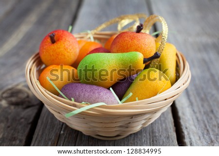 Bright Fruit shaped candies in macro image of marzipan sweets in a basket on the wooden table