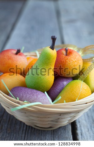 Fruit shaped candies in macro image of marzipan sweets in a basket on the wooden table
