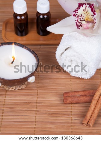 Spa still life with aromatic candle, orchid flower, towel, aromatic oils and cinnamon sticks