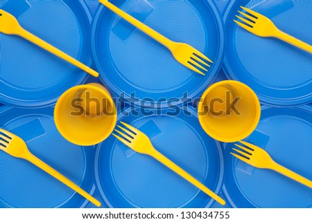 bright blue and yellow plastic disposable tableware on wooden background close-up, background