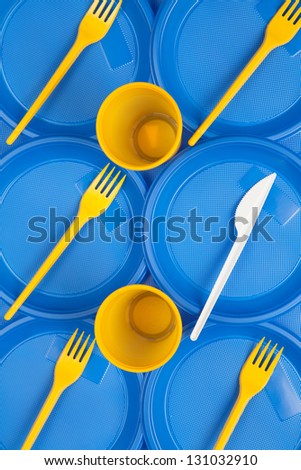 Bright blue and yellow plastic disposable tableware close-up, forks and knife, background