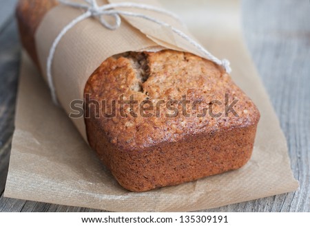 Banana bread with nuts in the baking paper on the wooden table, selective focus
