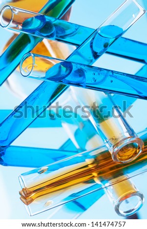 Test tubes with colored liquid (yellow and blue) on a light blue background