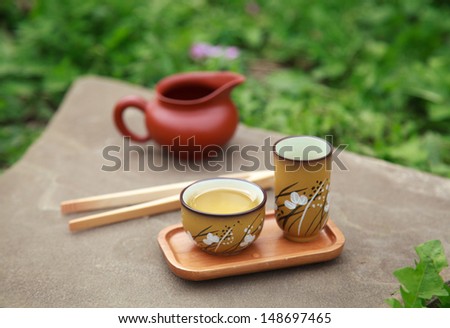 Traditional chinese tea ceremony accessories (tea cups and pitcher) on the stone table, selective focus on cup