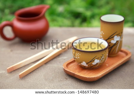Traditional chinese tea ceremony accessories (tea cups and pitcher) on the stone table, selective focus on cup