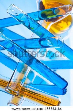 Test tubes with colored liquid (yellow and blue) on a light blue background, close-up